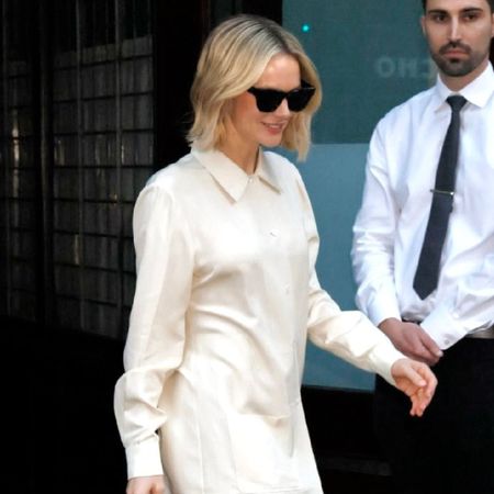 Carey Mulligan steps outside wearing cream trousers with a matching top and black sandals.