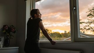 Woman looking out of the window at sunset, representing a loss of concentration in the early signs of burnout