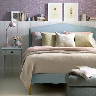 pastel bedroom with bed with cushions bed side table with lamp photo frame