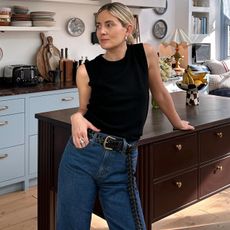 British influencer Lucy Williams poses in her stylish London kitchen wearing an outfit from J.Crew including a black tank top, woven black belt and jeans