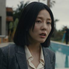 Seoyeon Jang as Eunice, standing outdoors in front of a pool, in episode 202 of Beef. 