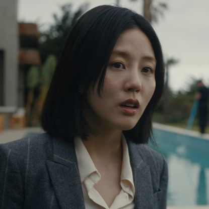 Seoyeon Jang as Eunice, standing outdoors in front of a pool, in episode 202 of Beef. 