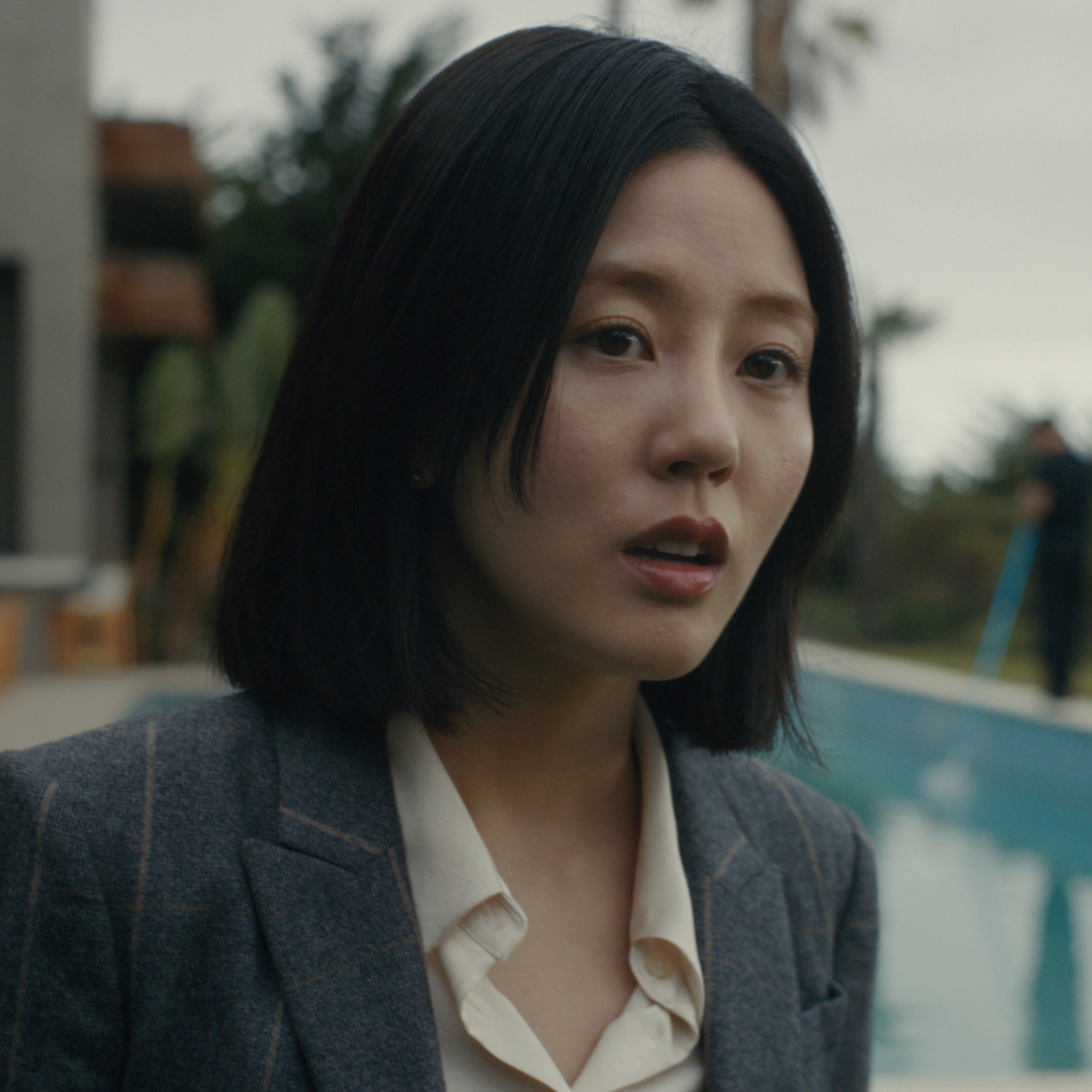 Seoyeon Jang as Eunice, standing outdoors in front of a pool, in episode 202 of Beef. 