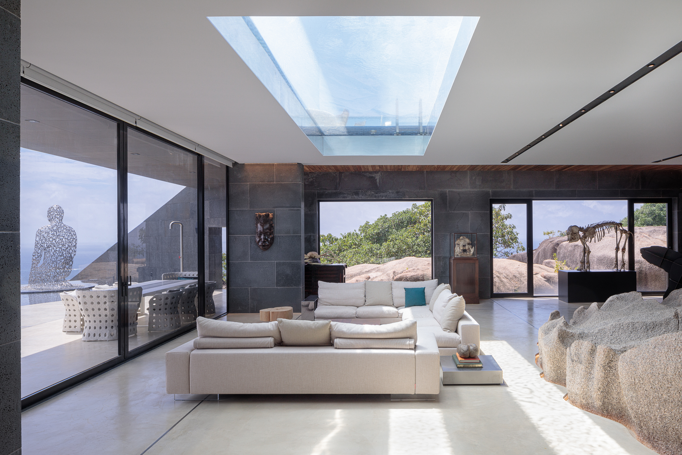 Open plan seating area with beige sofas and glass doors with views of the ocean
