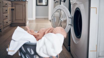 Close up of laundry basket of freshly washed towels beside a washing machine to support a guide on common heated airer mistakes to avoid to dry clothes quicker