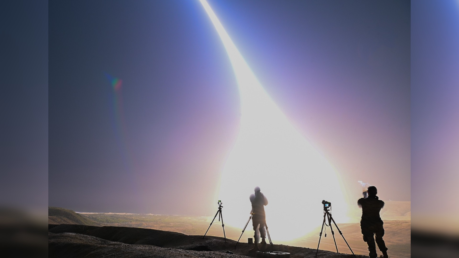 a bright streak of light arcs from the ground to the sky