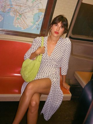 Jeanne Damas wears a polka dot dress from Rouje, red lips, and messy updo as she rides the New York subway