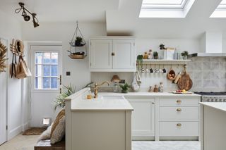 White kitchen with Shaker-style units, white worktop, brass handware and panelled splashback