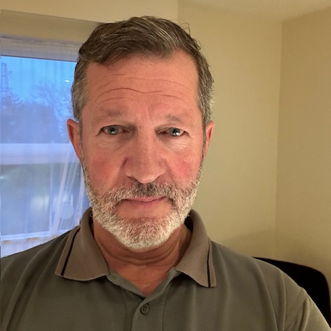 male with grey hair and beard wearing polo shirt