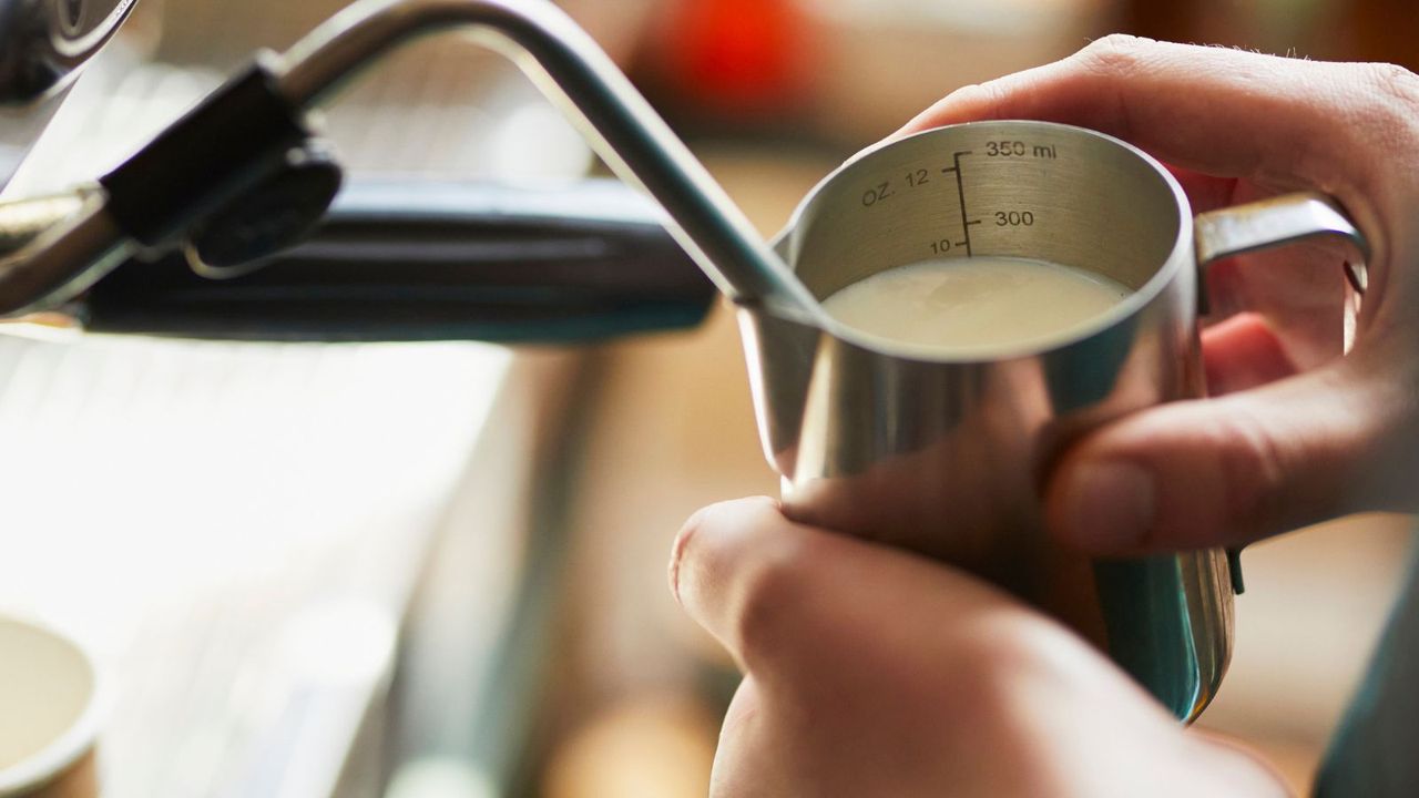 A barista steaming milk on a machine