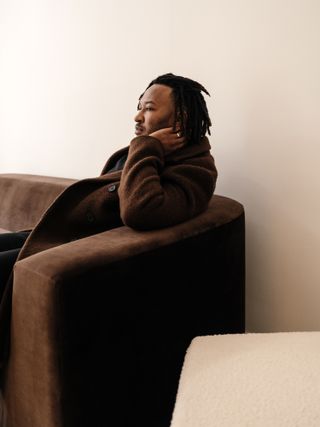 Designer Evan Jerry sitting on brown sofa by Studio Anansi