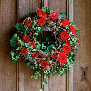 christmas wreath with red roses on wooden door