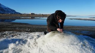 Utah State Parks ranger Allison Thompson investigates one of the crystalline mounds of mirabilite that have emerged this winter above the waters of the Great Salt Lake.
