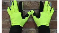 A pair of Endura Strike gloves are shown on hands held up against a brick wall and are a great winter cycling glove for affordability 