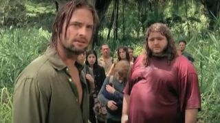 Josh Holloway looking off into the distance with Jorge Garcia and other cast members behind in the jungle in Lost