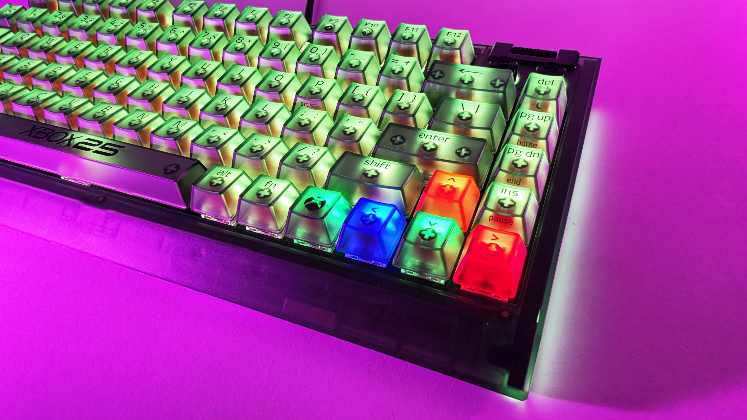 Angled perspective of the Razer BlackWidow V4 75% keyboard under pink light, highlighting multicolored illuminated arrow and modifier keys.