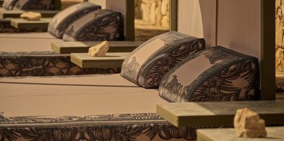 A beach club features earthy lounging booths decorated with hand-drawn natural motifs in muted dark blue against a muted pale rose background.