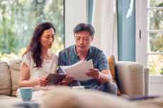 2HMH0NB Mature Couple Sitting On Sofa At Home Reviewing Personal Finances On Laptop