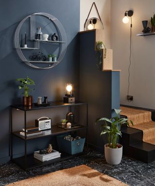 A dark blue entryway with a black shelving unit decorated with decor