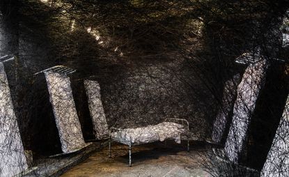 Image of single beds and room covered in black web like material