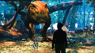 A boy standing in front of the interactive T. rex at the American Museum of Natural History. We see the silhouette of the boy against the large T. rex dinosaur looking down at him from a jungle.