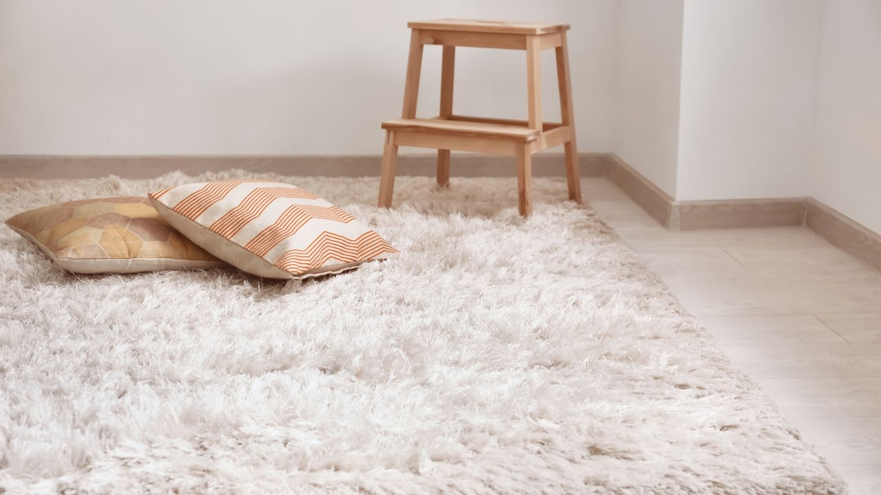 Beige carpet with throw pillows on floor and wooden step stool