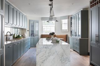 a light blue kitchen with a marble island