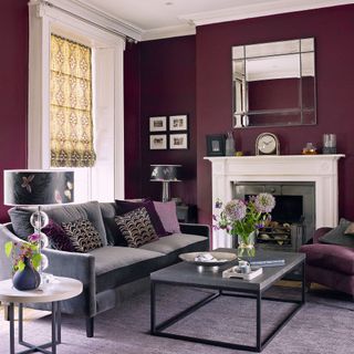 Dark purple living room with white fireplace, mirror, coffee table, sofa and window with blinds