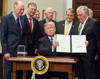 President Donald Trump holds up his Space Policy Directive 1, which directs NASA to return astronauts to the moon, after signing it in the Roosevelt Room of the White House on Dec. 11, 2017.