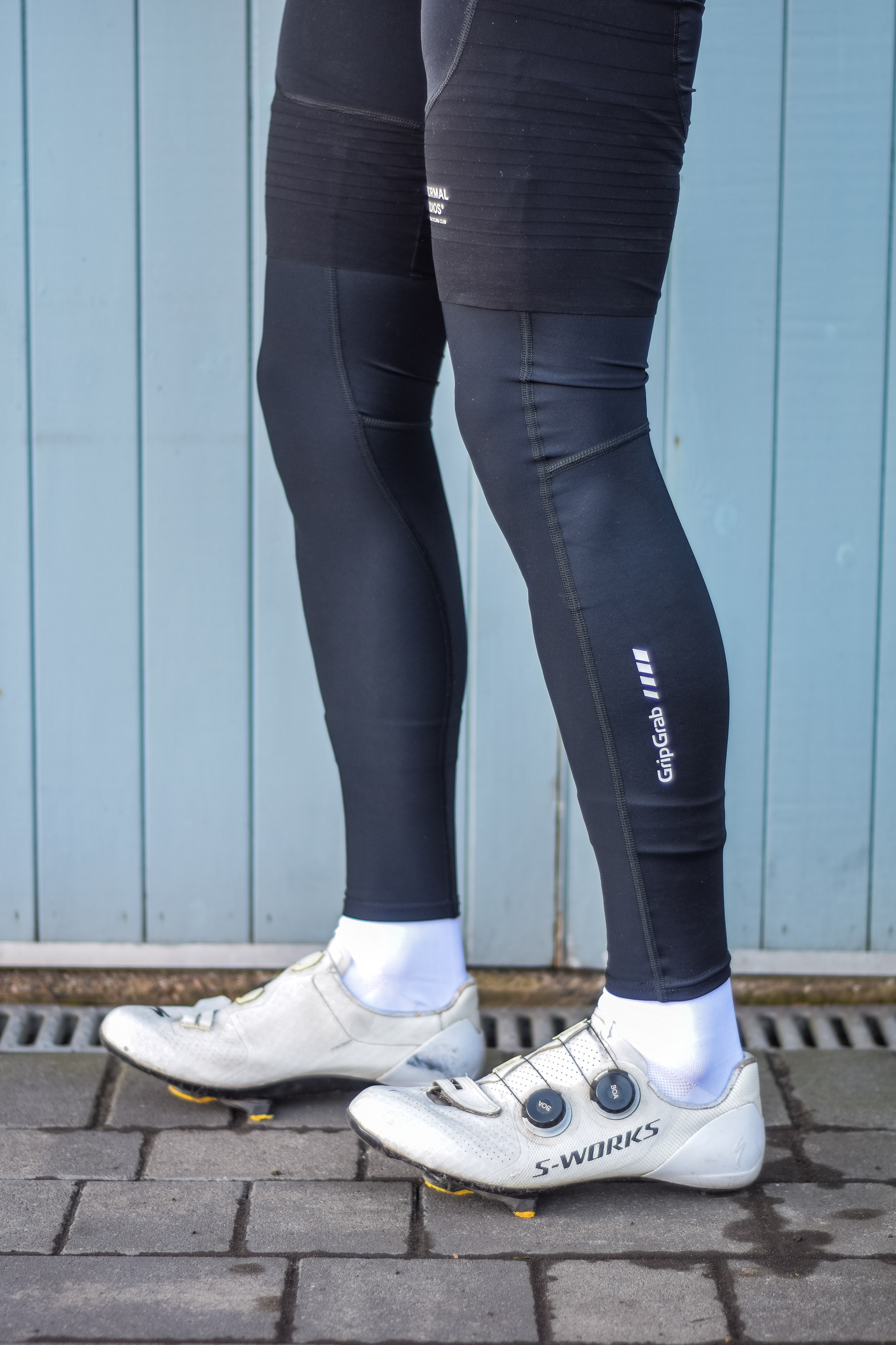 A man wearing cycling shorts and leg warmers in front of a blue door 