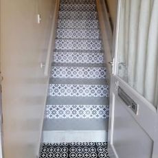 hallway with cream wall staircase and black white patterned flooring