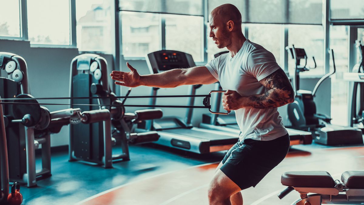 Man performing single-arm cable row in gym