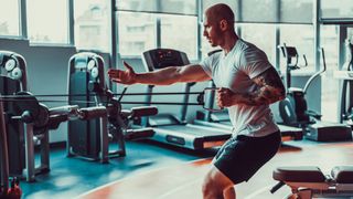 Man performing single-arm cable row in gym