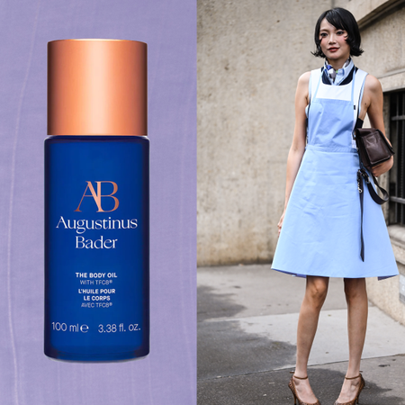 A woman with a short flipped bob hairstyle wearing a blue and white dress with cheetah print heels and holding a brown bag. She is next to a bottle of body oil.