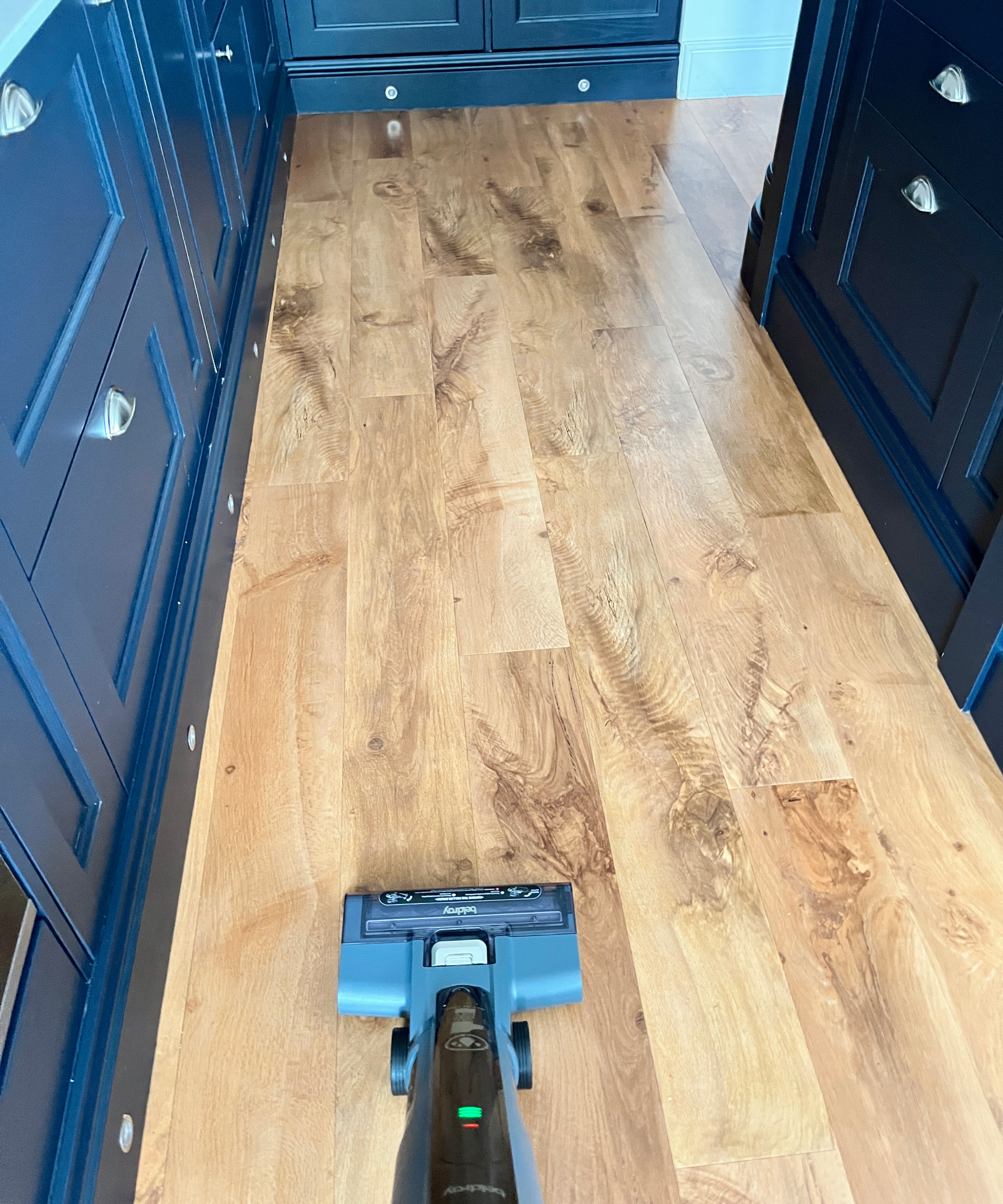Beldray All-In-One Multi-Purpose Floor Cleaner being used on LVT oak-effect flooring in kitchen with navy cabinetry