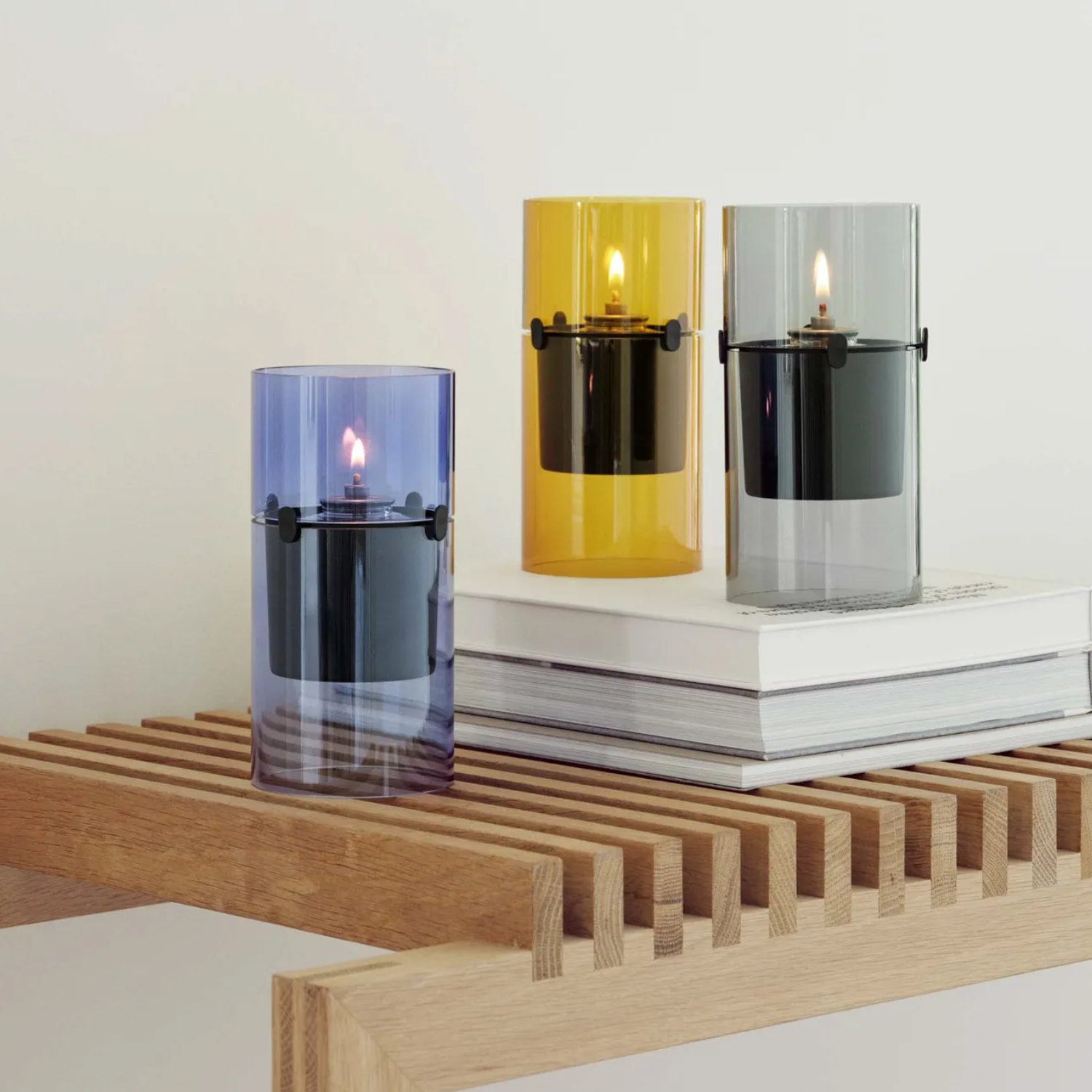 Blue, yellow, and black glass oil lamps on a wooden bench by a stack of books