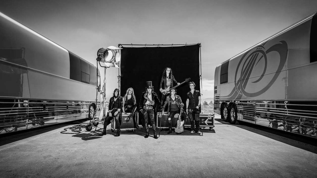 Alice Cooper and band sitting on flight cases in between two tour busses