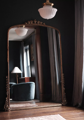 black standing mirror in a dark toned room