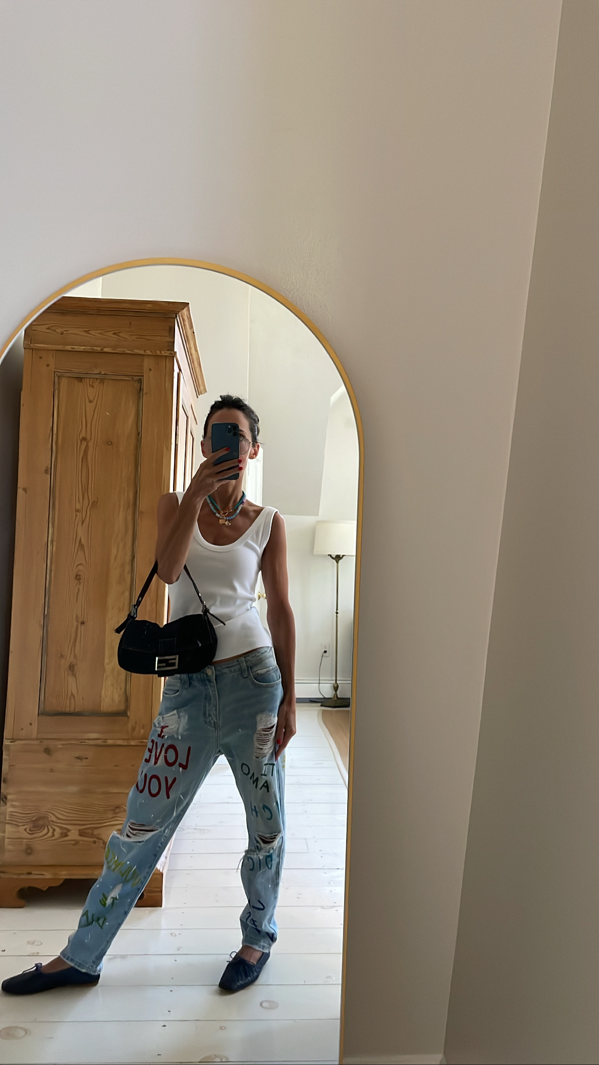 Larissa Mills wearing a white tank top and blue jeans outfit