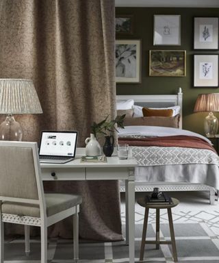 A dark neutral bedroom with a room divider separating a small bedroom office desk