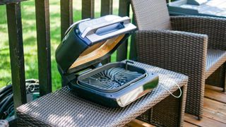 Ninja Foodi Smart XL 6-in-1 indoor air frying grill being used outdoors.