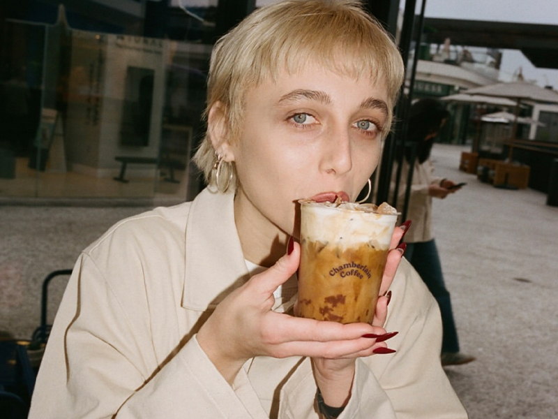 emma wers trench coat and drinks coffee