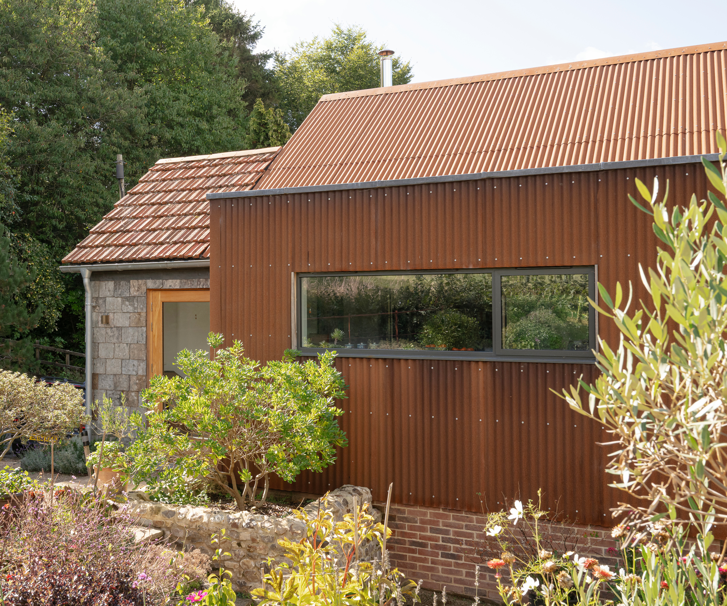 modern corten steel and stone clad self build with planting around exterior