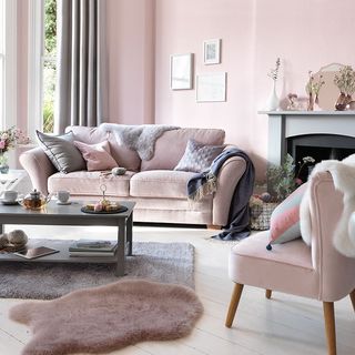 living room with light pink wall and pink sofa set with teapoy on grey floor mat