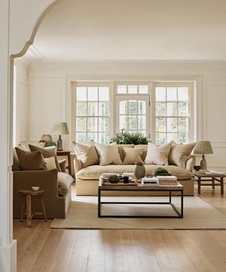 neutral living room with a velvet pillow back sofa and pops of soft light brown