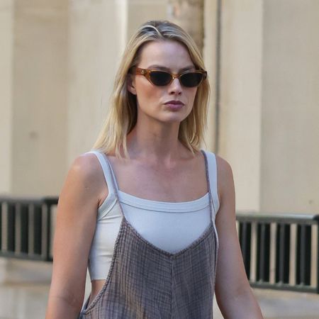 Margot Robbie wearing a casual knit jumpsuit over a white sports bra with suede Tory Burch slides in Paris