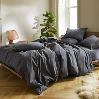 a bed with dark grey sheets