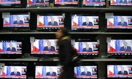 A woman walks past television screens showing Silvio Berlusconi&amp;#039;s farewell speech Sunday: The controversial leader may be gone, but it won&amp;#039;t be for long, say critics.