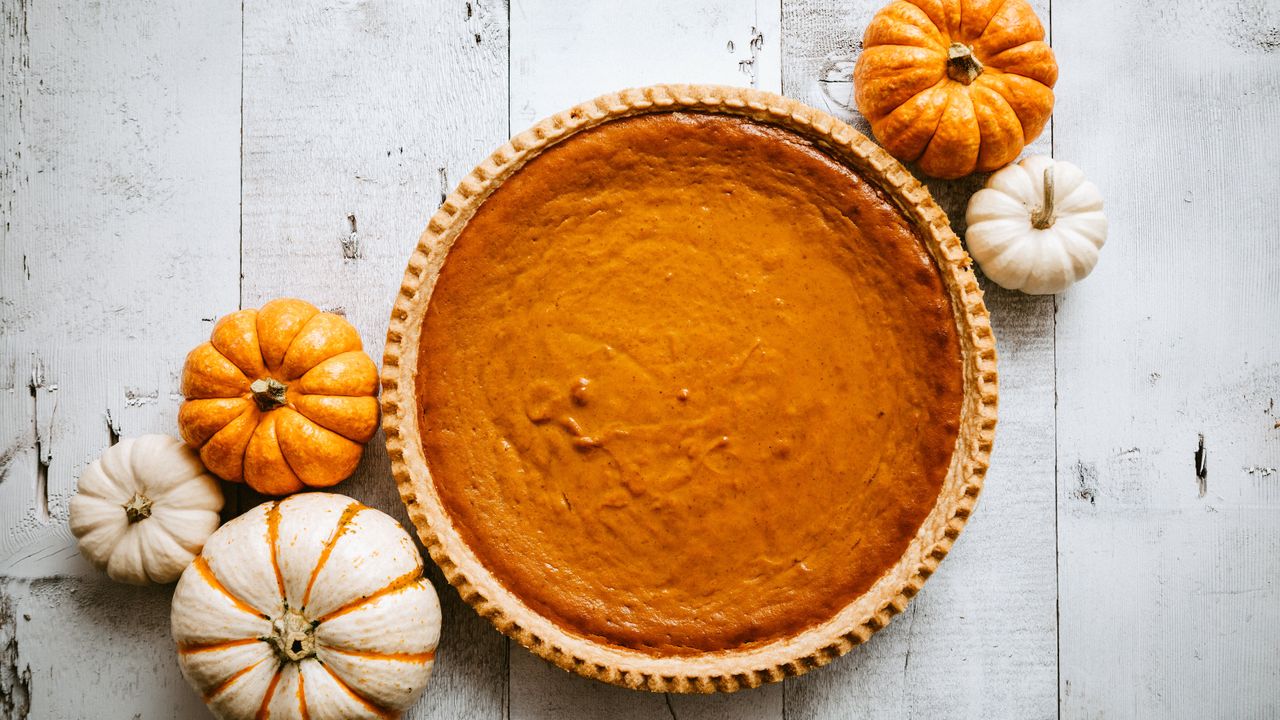 Classic pumpkin pie shot from above with decorative pumpkins around it