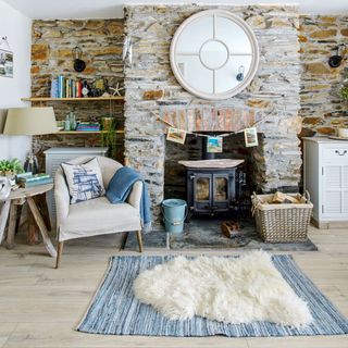 A coastal living room with a log burner and an exposed brick wall